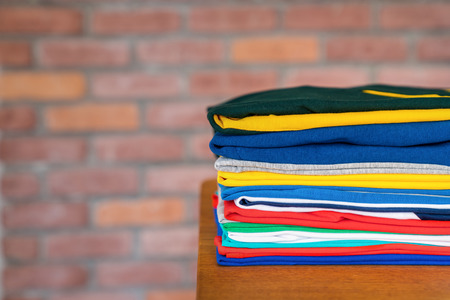 Stack of folded clothes on table indoor.Fresh folded cotton clothingの写真素材