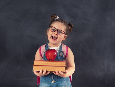 Little cute child holding books on blackboard.Education conceptの写真素材