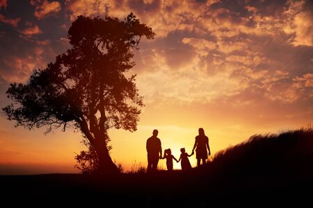 Happy family silhouette standing on against sunset time.の写真素材