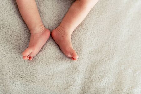 Legs of new born baby is sleepin on the bed.