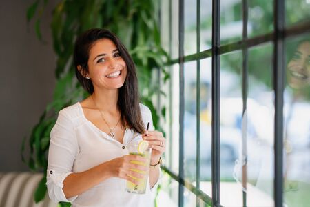 Young woman smiling and drinking some beverage in a cafe.の写真素材