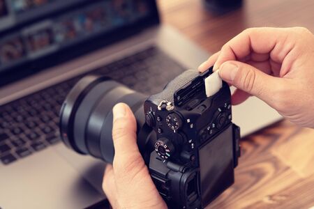 Photographer inserting or removing a memory card in professional camera.の写真素材