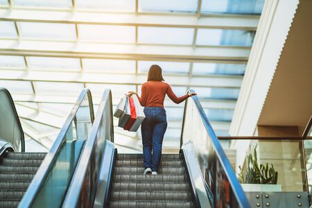 Young woman is walking on the escalator in a mall and shopping.の写真素材