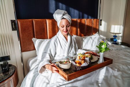young woman having her breakfast in bed with pleasure.の写真素材