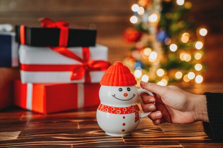 Holding a cup with christmas present concept and decorated christmas tree. New year concept.の写真素材