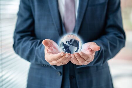 Businessman is holding world sphere. concept of beeing connected and ruling the world, global dominationの写真素材