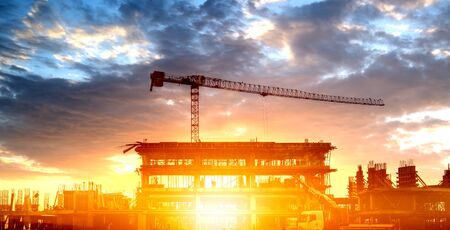 Silhouette of a building with a construction crane against the clouds.の写真素材