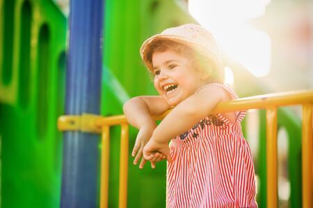 Little cute girl playing in playground an wearing hat. Concept play in outdoors in summer timeの写真素材