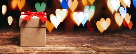 gift box on wooden table with shiny heart shaped lights