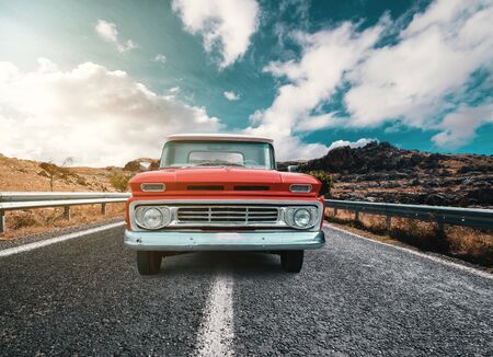 A Classical automobile on a journey on the country raod against the cloudy and blue sky.の写真素材