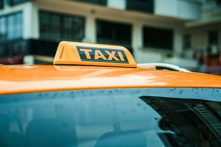 Close up yellow taxi sign on the roof of a car. Transport and travel concept