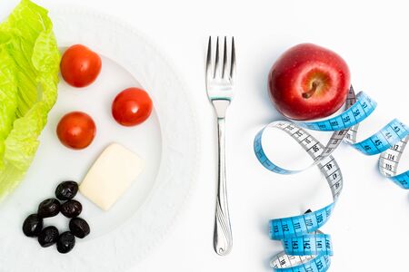 isolated red apple and plate of healthy meals next to tape measuring on white background. Diet and healthy living conceptの写真素材