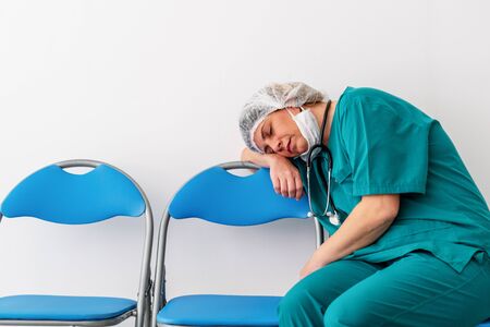Woman doctor is sitting and fall asleep, because of worry, frustration, tiredness and exhausting of global infection covid-19の写真素材