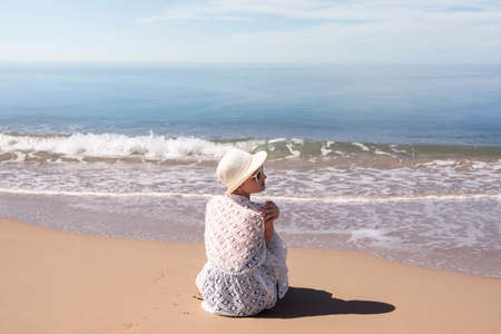 Beautiful woman sitting on golden fine sand enjoying the idyllic scene of the sun, sand and sea. Beautyful sandy beach in Side Antalya. Quality photoの写真素材