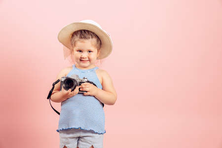 Little girl holding old vintage camera and smiling on pink background.の写真素材