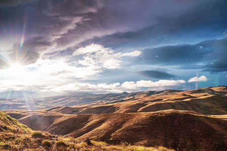 Hills and rural landscape with Cloudy Sky and sunbeam In The Background. High quality photoの写真素材