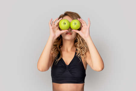 Beautiful woman is holding two apples to face. Healthy lifestyle and dieting concept. High quality photoの写真素材