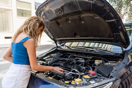 Young woman is looking to open car hood for troubleshoot. Transportation and vehicle concept. High...