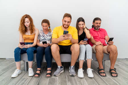 Group of friends sitting couch and looking to their mobile phones. Technology addiction concept. High quality photoの写真素材