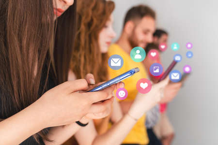 Group of friends standing and looking to their mobile phones. Social media and technology addiction concept. High quality photoの写真素材