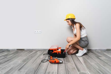 Young woman with toolbag is taking some tools for repairing the maintenance at home. High quality photoの写真素材