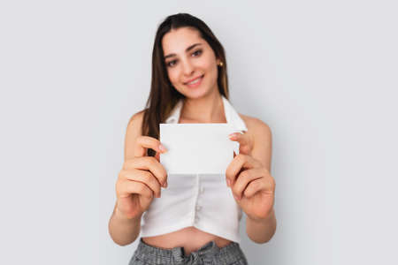 Young brunette woman is holding a blank note paper for mock up use. Silent communication concept. High quality photoの写真素材