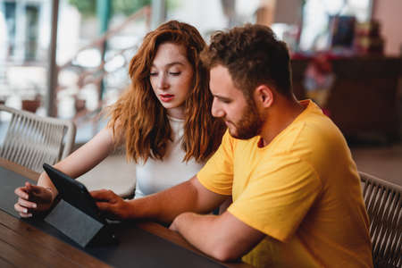 A coung couple friends or colleague sitting in cafe and looking to a tablet. High quality photoの写真素材