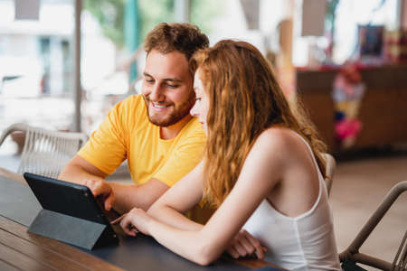 A coung couple friends or colleague sitting in cafe and looking to a tablet. High quality photoの写真素材