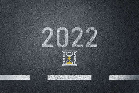New year 2022 on asphalt road surface with sandglass icon. High quality photo