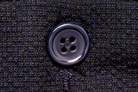 Macro photo of a sewing button on a dark blue fabric pattern isolated background. High quality photo
