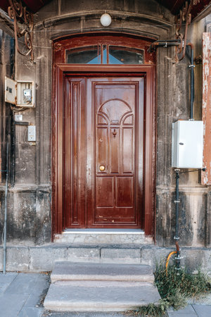 Old classical stone house with rustic, brown, carved, vintage wooden door. Door textures and backgound. High quality photo.の写真素材