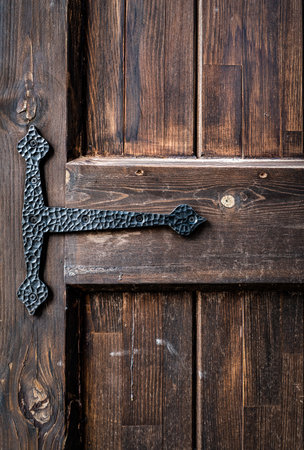 An old grungy, brown, natural wooden door part with grains and with black metal hinge, for background and texture. High quality photoの写真素材