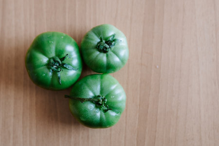 Three green tomatoes on a wooden surface. High quality photoの写真素材