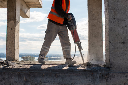Construction worker using jackhammer to drill concrete floor. High quality photo
