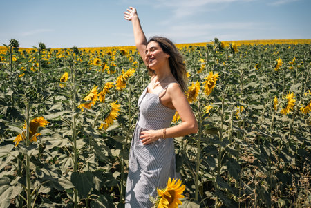 Happy woman arms raised and enjoying in sunflower field. High quality photoの写真素材