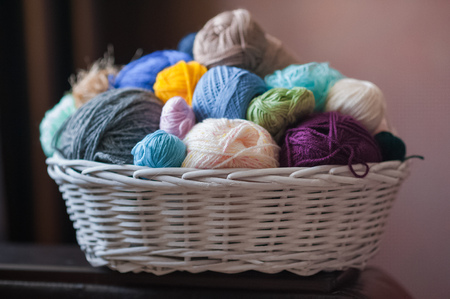 Colorful yarn balls in wicker basket isolated on whiteの写真素材