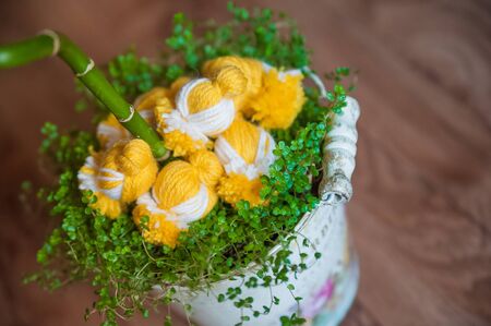 Easter decor of chicks and spring grass. Knitted chickens on the grass. Handmade chicken in a vintage pailの写真素材