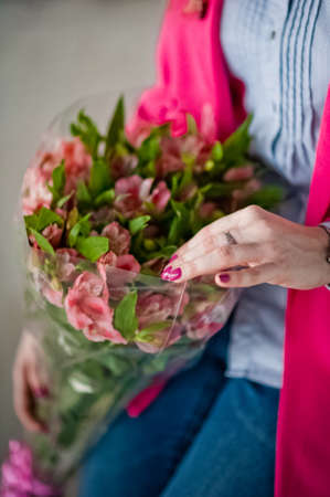 A young girl is holding spring flowers in her hands. A girl and a bouquet of beautiful bright flowersの写真素材