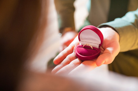 Wedding ring. The man holds a ring in his hand and makes an offer.の写真素材