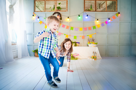 Merry Easter picture of mother and baby boy. A woman plays with her son in a decorated interior. He runs away from his mother and laughs.の写真素材