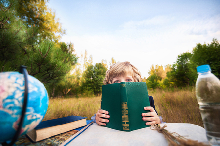 The first grader is sitting at the table. The schoolgirl with a bottle of water. Day of knowledge, the beginning of the school year,の写真素材