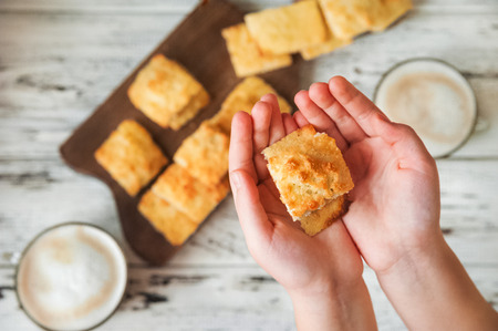 Homemade coconut biscuits and hot cocoa mugs on a light wooden background. The child is holding cookies at home. Place and background for your text.の写真素材