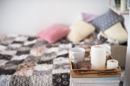 Beautiful spring decorated interior in white textured colors. Bedroom, bed on wooden pallets. A cup...