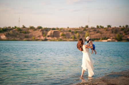 Young mother with her son on the beach on a sunset background. Unplugged mindfull.の写真素材