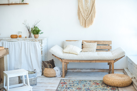 Beautiful spring photo of a kitchen interior in light textured colors. Kitchen, living room with beige couch, large cactus and woven macrame on the wallの写真素材