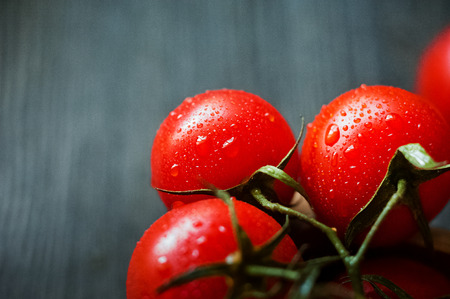 Ripe juicy beautiful tomatoes with water drops on a dark background closeupの写真素材