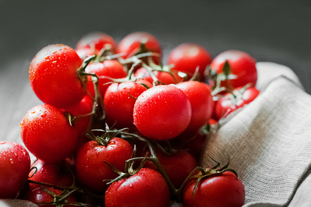Ripe juicy beautiful tomatoes with water drops on a dark background closeupの写真素材
