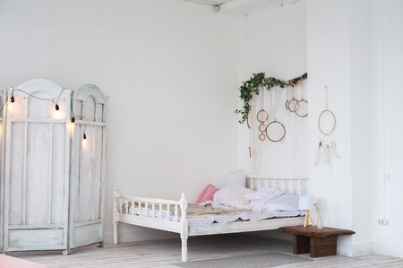White textured bedroom in the style of shabby. Bed in an ecological style and Loft style. Rustic dream catchers on a white wall. screenの写真素材