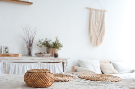 The white textured kitchen is blurred in the background in the style of shabby. A large table in an ecological style and loft style. Rustic napkins, wicker baskets, diyの写真素材
