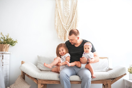 Relationship with young children and father. Dad hugs two daughters on the couchの写真素材